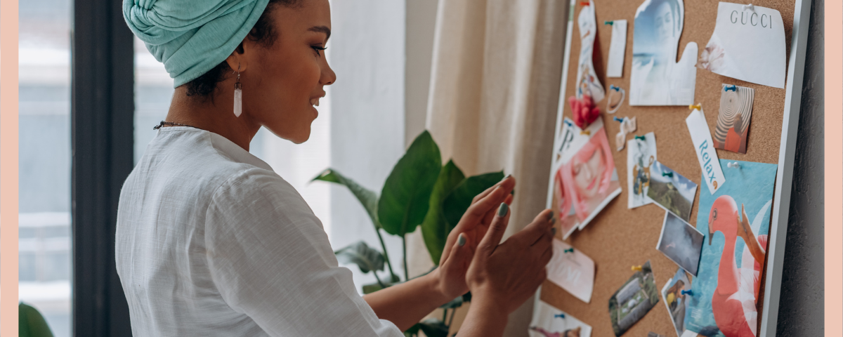 a woman standing in front of a cork vision board