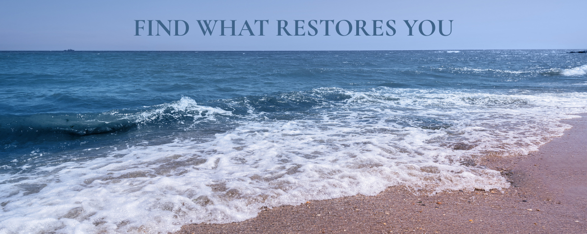 Ocean waves gently rolling onto a sandy beach beneath the words "Find What Restores You," representing peace, restoration, intentional living, and self-care.