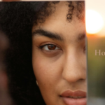 Woman looking at her reflection in a mirror at sunrise with the words "How Are You... Really?" encouraging a quiet moment of self-care and personal reflection.